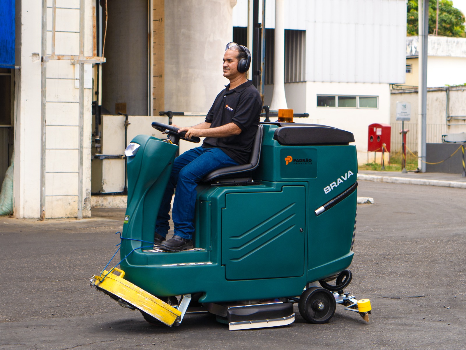 Colaborador da Padrão Serviços operando lavadora de piso automatizada em galpão industrial